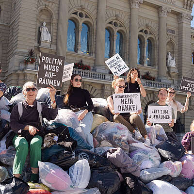Davanti al Palazzo federale, alcune persone sono in piedi intorno a un’enorme montagna di vestiti. Hanno cartelli e bandiere in mano. Protestano contro l’industria della fast fashion, dannosa per l’ambiente e disumana.