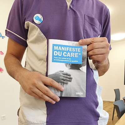 Un travailleur en EMS tient le Manifeste du Care dans ses mains.