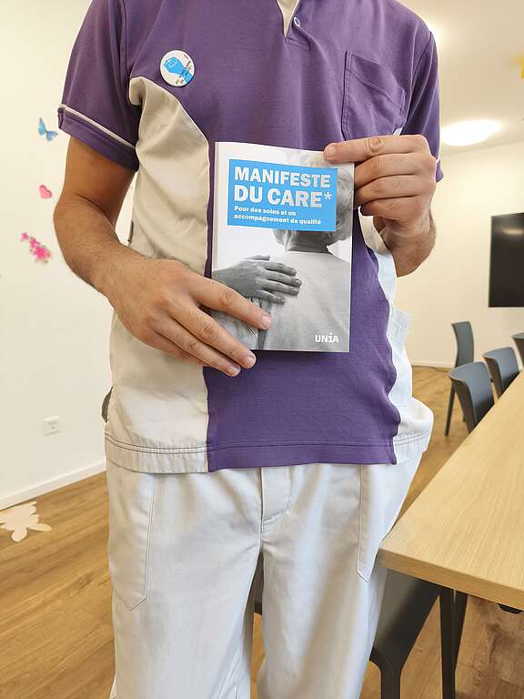 Un travailleur en EMS tient le Manifeste du Care dans ses mains.