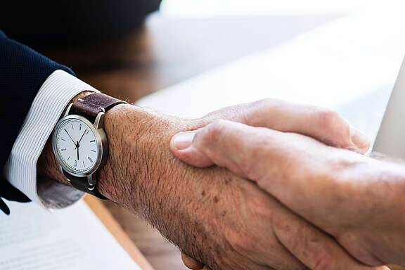 Handschlag zwischen älterem und jüngerem Mann