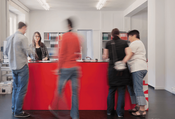 Des personnes se tiennent à la réception d'un secrétariat d'Unia