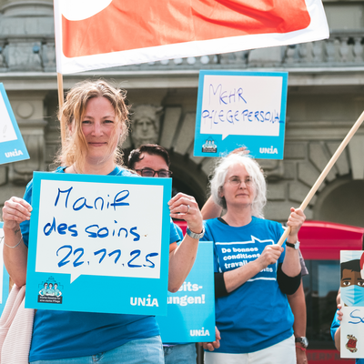 Menschen an eine Pflege-Demo mit Schildern auf denen steht: 