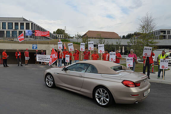 Des syndicalistes d’Unia avec tracts et banderoles au bord d’une route.