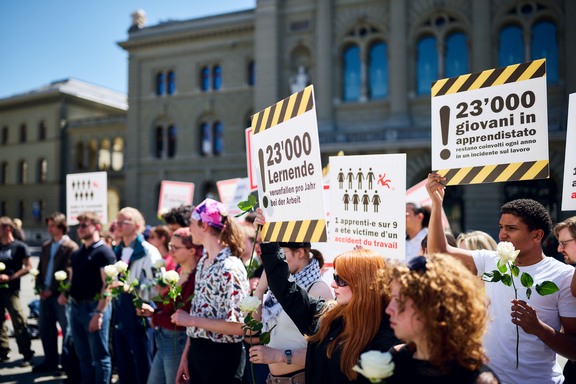 Devant le Palais fédéral, des mains qui portent des pancartes avec l'inscription 