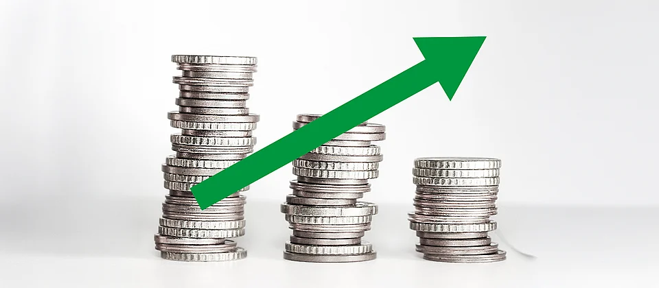 Salari e potere d’acquisto in calo: le pile di monete sempre più piccole con la freccia rivolta verso l’alto simboleggiano la perdita di salario reale e la necessità di aumenti salariali.
