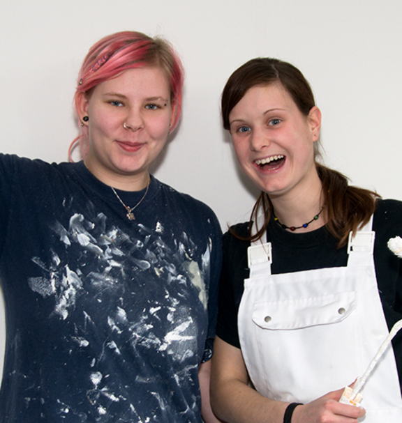 Due giovani pittrici di fronte a un muro.