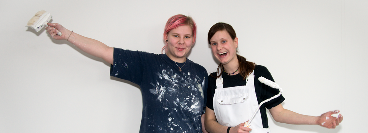 Due giovani pittrici di fronte a un muro.