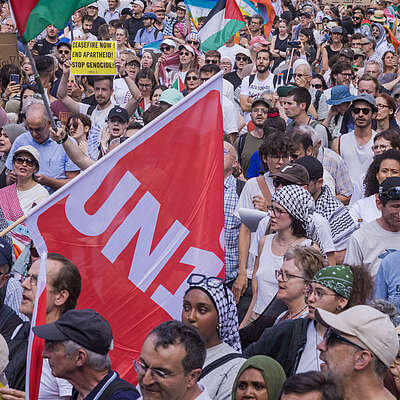 Folla alla manifestazione di solidarietà per Gaza con al centro la bandiera di Unia