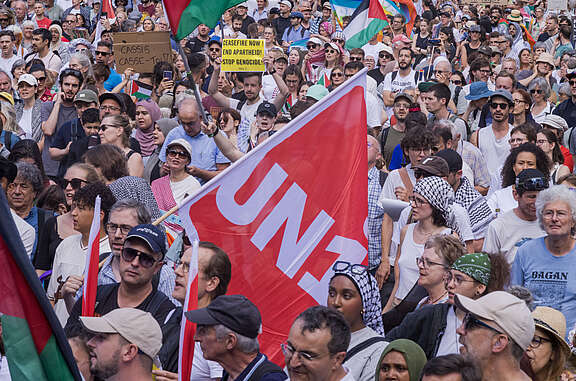 Folla alla manifestazione di solidarietà per Gaza con al centro la bandiera di Unia