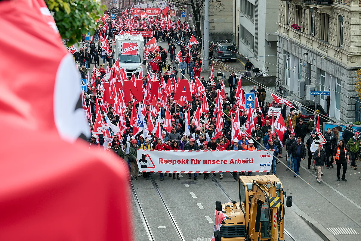 Bauarbeiter ziehen an einer Demo mit zahlreichen Unia-Fahnen und einem grossen Transparent mit der Aufschrift «Respekt für unsere Arbeit!» durch die Strasse.