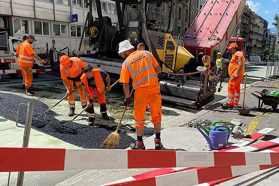 Des travailleurs appliquent de l'asphalt en pleine chaleur