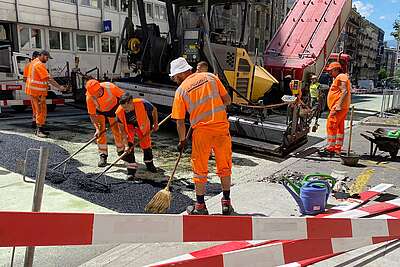 Des travailleurs appliquent de l'asphalt en pleine chaleur