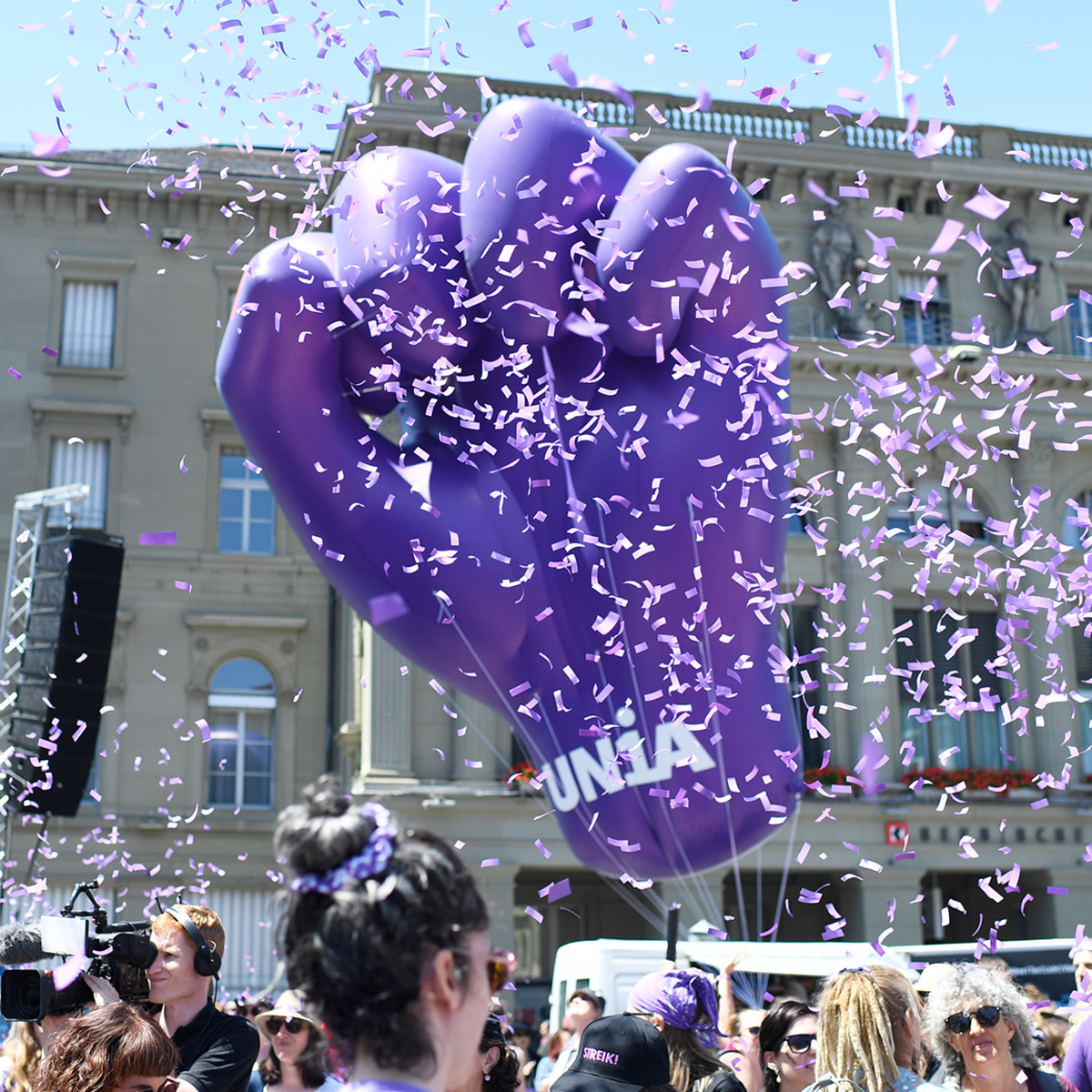 Grosse, violette Faust als Ballon mit lila Confetti, die in der Luft rumfliegen