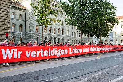 Menschen ziehen mit einem Banner die rote Linie vor dem Bundeshaus