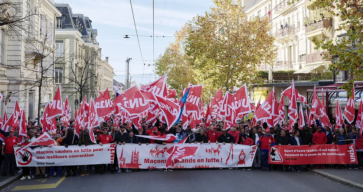 La tête d'une immense manifestation de travailleurs de la construction avec de nombreux drapeaux Unia à Lausanne