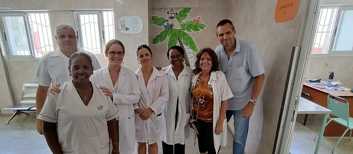 Six employés de l’Hôpital El Cerro, dont cinq femmes et un hommes, sont en habits de travail dans une salle d’attente. Ils posent pour une photo en compagnie de Beat Schmid, co-président de l’Association pour l’aide médicale Centro América (AMCA) et membre de mediCuba.