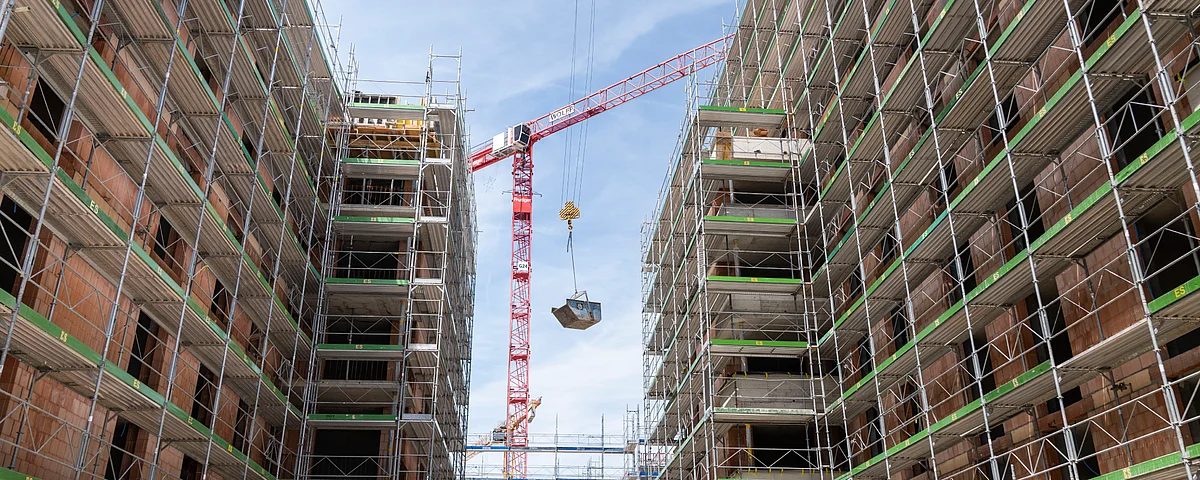 Un grande cantiere con tre facciate coperte da ponteggi.