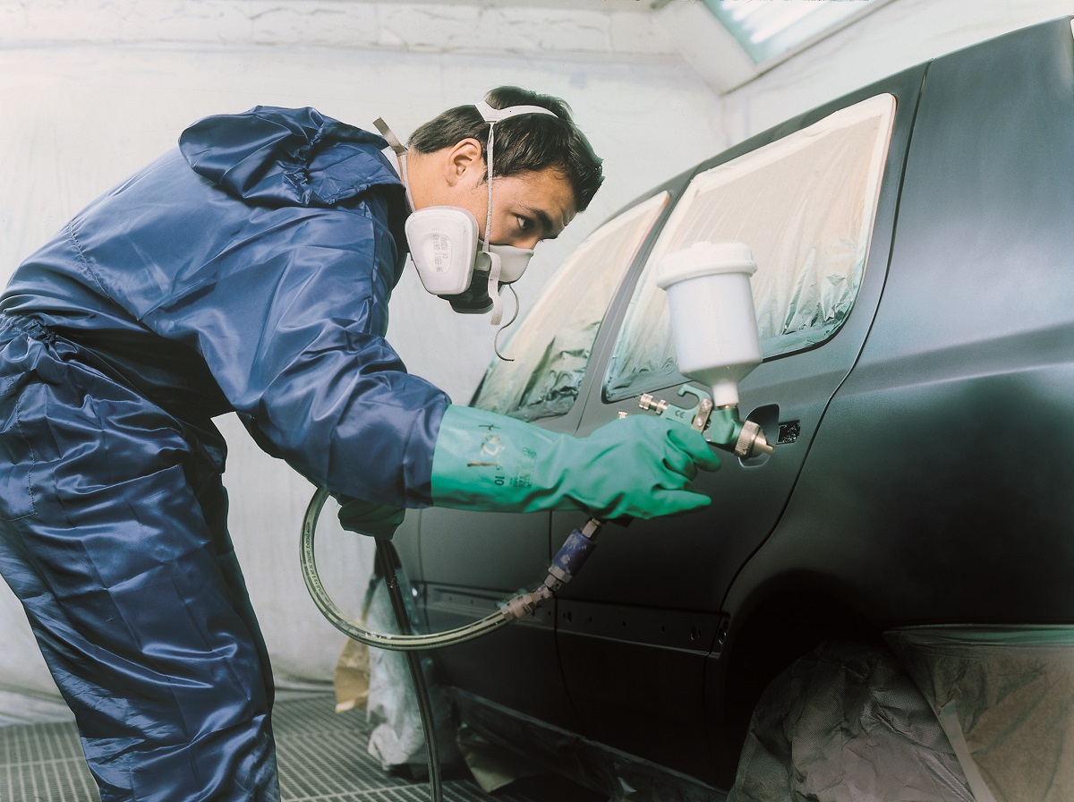 Un peintre en carrosserie peint un véhicule