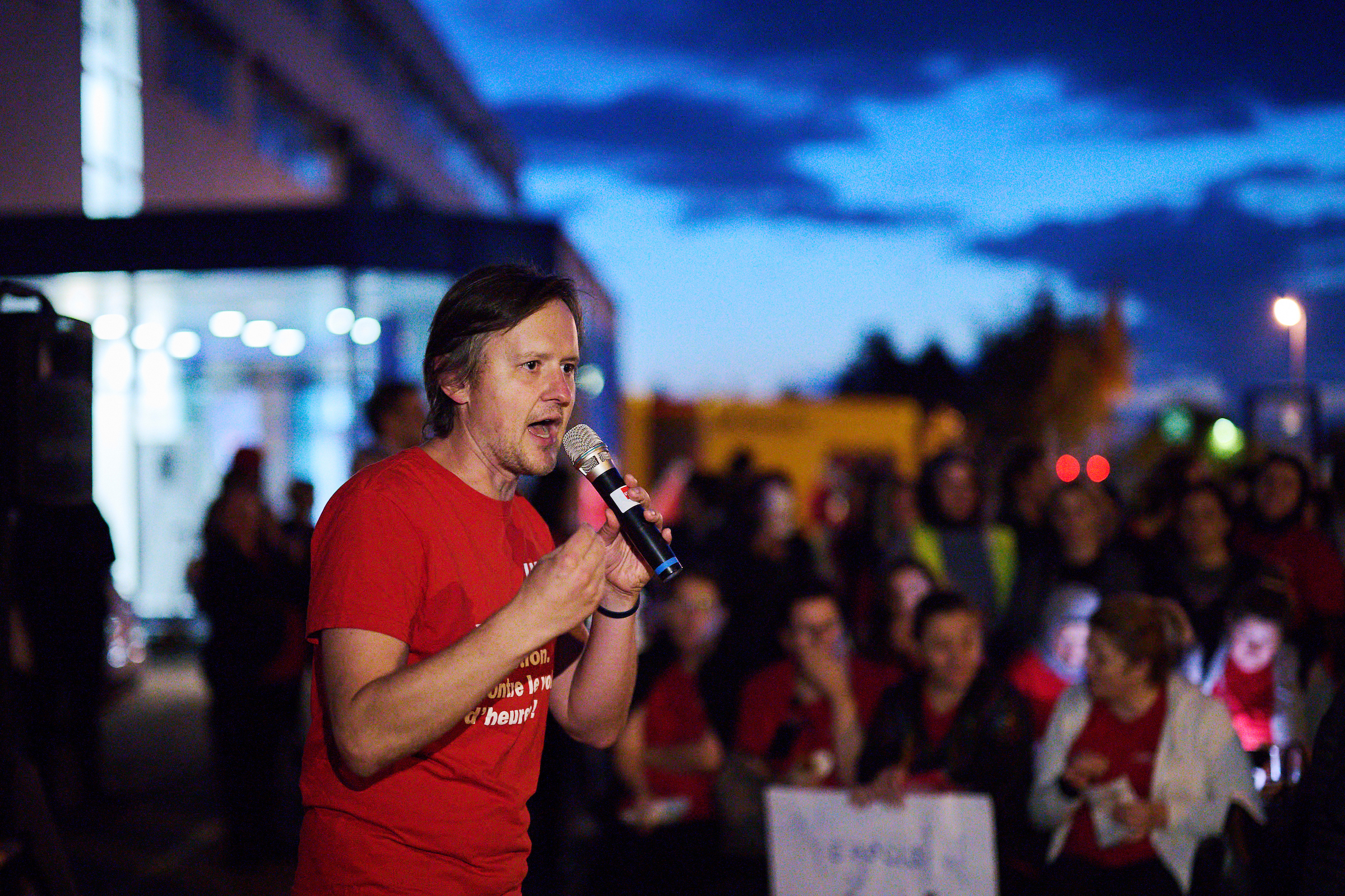 Roman Künzler, responsable de la logistique d'Unia, tient un discours à un micro lors d'une assemblée en plein air.