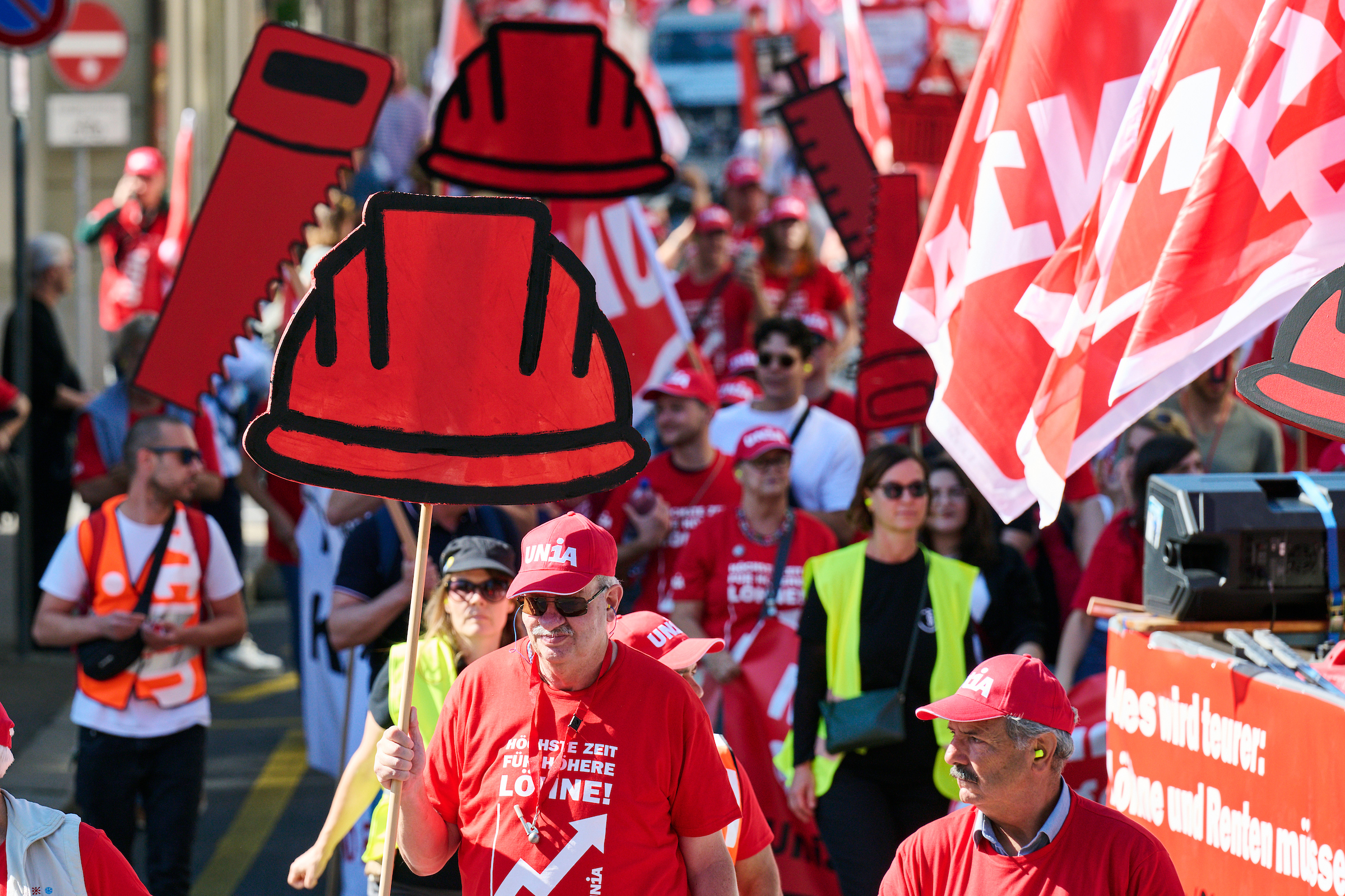 Les ouvriers du bâtiment participent à la manifestation pour les salaires à Berne. Ils expriment leurs revendications pour des salaires plus élevés avec des panneaux en formes de casque de protection, des banderoles et des T-shirts avec le texte «Il est grand temps d'augmenter les salaires».