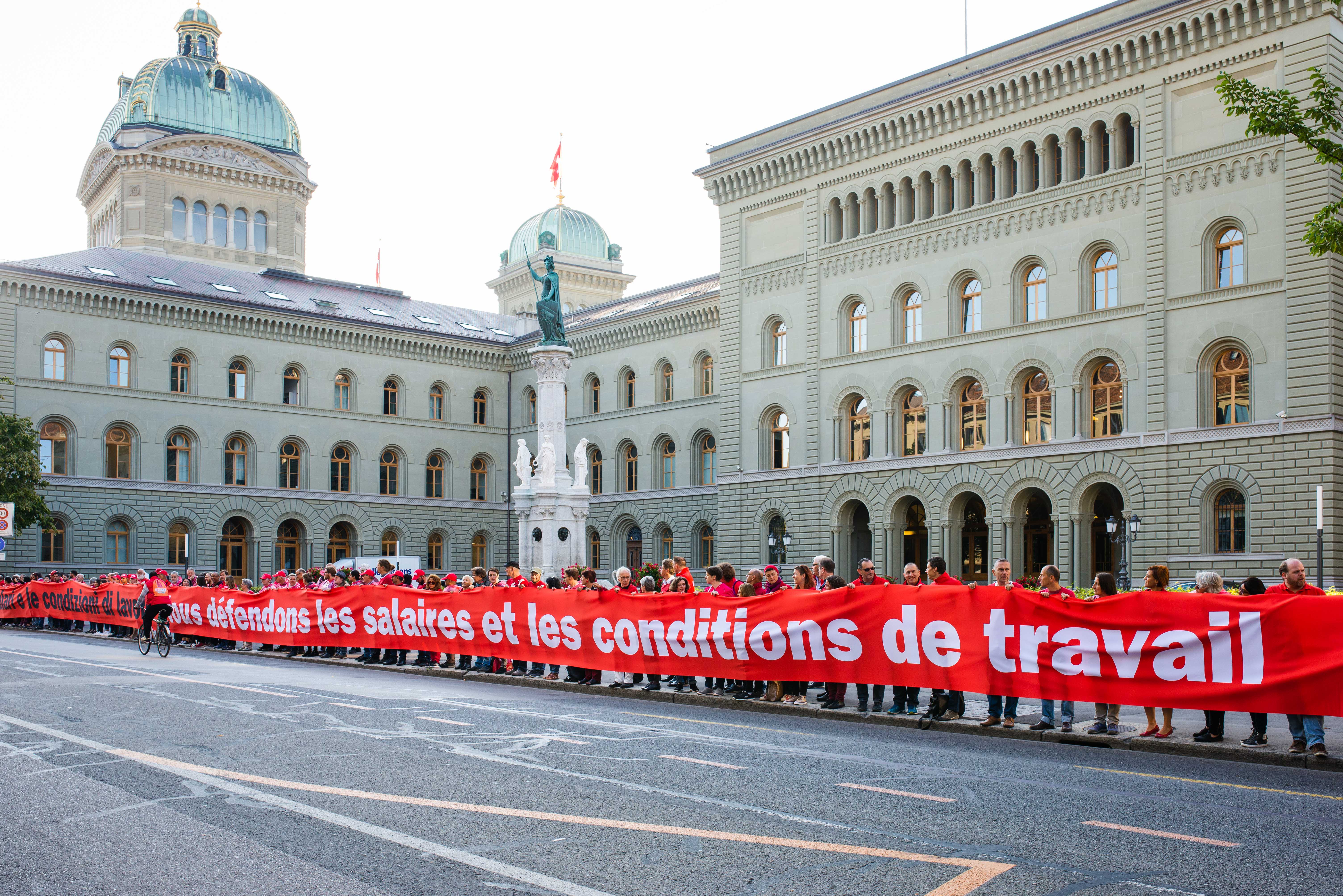 Des activistes d’Unia portent une banderole sous forme d’une ligne rouge pour la protection des salaires